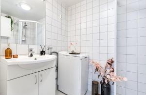 a white tiled bathroom with a sink and a washer at Charming Duplex near the beautiful Akerselva river in Oslo +12 photos