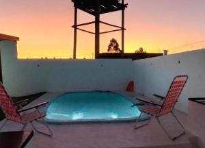 a swimming pool on a patio with two chairs at Casa de Campo El Molino in Federación