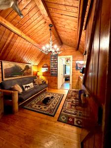 ein Wohnzimmer mit einer Couch und einem Kronleuchter in einer Hütte in der Unterkunft The Dapper Duck Log Cabin in Cosby