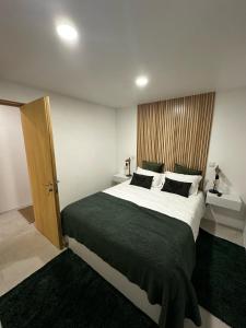 ein Schlafzimmer mit einem großen Bett und einer Holztür in der Unterkunft Casa do Lago das Freiras in Ribeira Grande