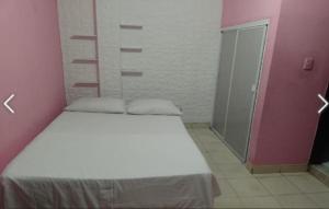 une chambre avec un lit blanc et un mur rose dans l'établissement Hotel Selecta, à Villavicencio
