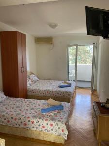 a room with two beds and a tv and a balcony at Apartmani Rakocevic in Sutomore
