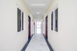 an empty corridor of a hospital with red doors and white walls at Hotel O Ramavarapadu Near PVR Icon in Vijayawada