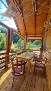 a dining room with a table and chairs on a wooden deck at Planinska koliba Šipovo 3 in Šipovo