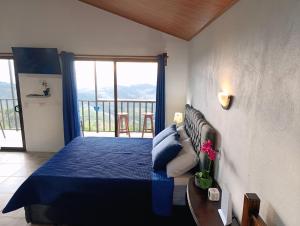 a bedroom with a blue bed and a balcony at Finca Alta Vista Monteverde in Monteverde Costa Rica