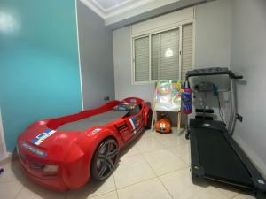 a bedroom with a red car bed and a treadmill at Comfortable & Well-Located Apartment Near Rabat in Oulad Akkou
