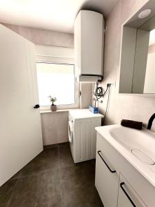 a white bathroom with a sink and a window at Villa Forever More in Kaštela