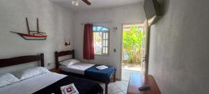 a bedroom with two beds and a window and a door at Pousada Vila das Artes in Paraty