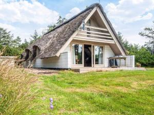 a small cottage with a thatched roof on a field at 5 person holiday home in Ringkøbing-By Traum in Nørby