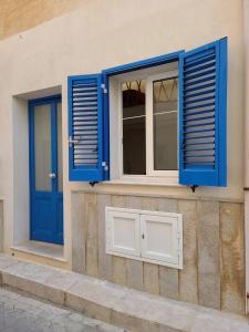 a building with blue shutters and a window with a door at Appartamento Nonno Pit, Marettimo in Marettimo