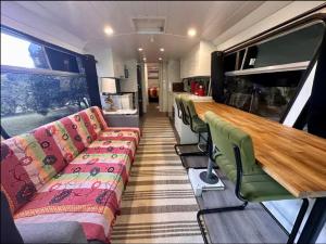 a train car with a long table and green chairs at Bello BigRig Luxury Riverfront Escape Close to Town in Bellingen