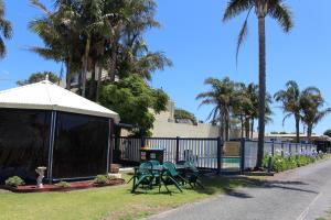 a group of chairs and a gazebo with palm trees at Golden Terrace Holiday Park in Lakes Entrance