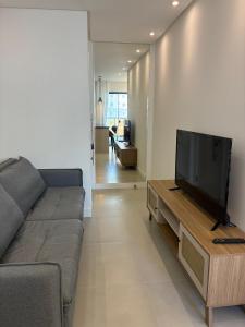 a living room with a couch and a flat screen tv at Apto Kairós Beach Stay - Piscina e Churrasqueira in Itapema +16 photos