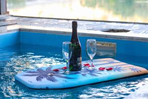 a bottle of wine and two glasses on a board in a swimming pool at Riverside Private Pool&Halal Suite in Shkodër