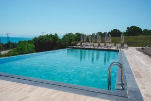 a large swimming pool with chairs and umbrellas at Lemon Suites & Restaurant in Korucuk