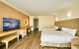 een hotelkamer met twee bedden en een tv bij Finest Guam Golf & Resort in Yigo