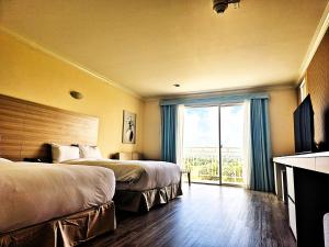 een hotelkamer met twee bedden en een groot raam bij Finest Guam Golf & Resort in Yigo