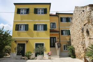 un edificio amarillo con ventanas con contraventanas verdes en Guest House Ankora, en Skradin