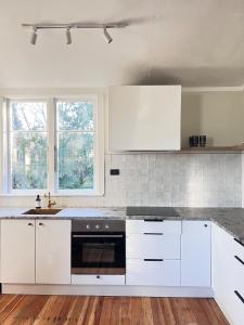 a kitchen with white cabinets and a black oven at Charming 100 year old Villa in Te Kuiti