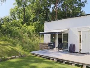 Cabaña blanca con terraza y mesa en Charming Cottage Surrounded by Nature, en Grimeton