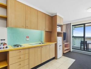 a kitchen with wooden cabinets and a view of the ocean at The Entrance Waterfront Apartment 505 in The Entrance