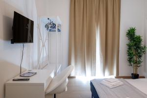 a white room with a desk and a television at Vacanze Cisternone Livorno centro in Livorno