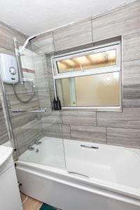 a bathroom with a tub and a window and a sink at 4 Bedroom House in Wolverhampton Sleeps 8 Ideal for Contractors in Fallings Park