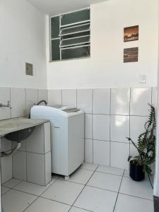a white tiled bathroom with a sink and a washing machine at Nossa casa, nosso lar in Belo Horizonte +27 photos