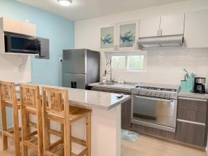 a kitchen with stainless steel appliances and wooden bar stools at Apartamento Fina Dream Lagoon in Veracruz
