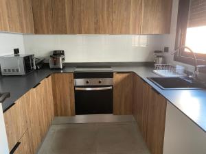 a kitchen with wooden cabinets and a black stove top oven at Habitación Grande en Apartamento Compartido in Sant Boi del Llobregat