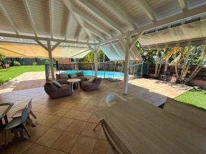 a patio with an umbrella and chairs and a pool at Villa Morne-Bou in Petit-Bourg