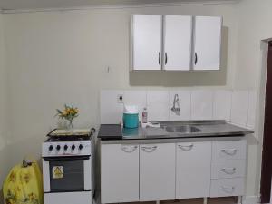 a kitchen with white cabinets and a sink and a stove at Casa Aconchegante in Vitória da Conquista