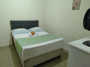 a small bed in a room with a white wall at Casa Aconchegante in Vitória da Conquista