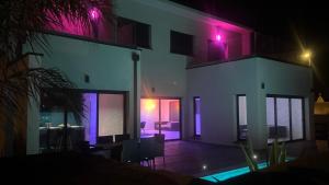 a house with purple lights on the side of it at Villa luxueuse Piscine Chauffée & SPA in Villetelle