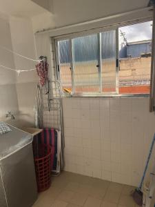 a kitchen with a window and a white tiled wall at Apartamento no centro de Mongaguá in Mongaguá +15 photos
