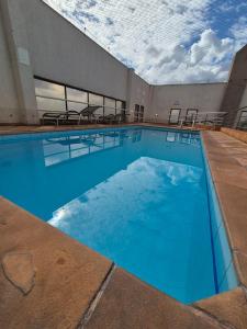 a large swimming pool with blue water in a building at Flat Luxo Golden Ingá - Centro, Ao Lado Shopping in Maringá