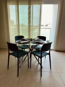 a glass table and four chairs in a room at Puerto Azul in Puerto Colombia