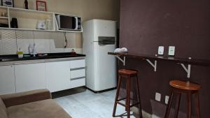 a kitchen with a refrigerator and two bar stools at Comodidades na Estrada do Coco in Camaçari