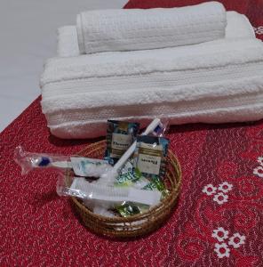 a basket of toothbrushes and toothpaste next to a bed at Comodidades na Estrada do Coco in Camaçari