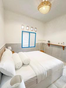 - une chambre avec un grand lit blanc et une fenêtre bleue dans l'établissement Tony's Villa 1233 Seahorse Lane Gili Trawangan, à Gili Trawangan