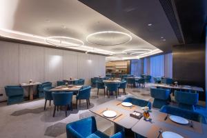 a dining room with tables and blue chairs at Orange Crystal Qingdao Taidong Pedestrian Street Yan'an Third Road Hotel in Qingdao