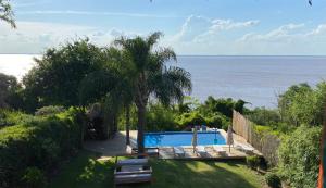 a swimming pool with a palm tree next to the ocean at Del Barranco in San Gregorio de Polanco