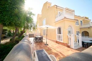 a view of a large house with an umbrella at Soleado adosado esquinero frente a piscina in Gran Alacant