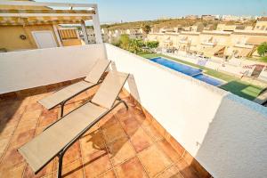 two chairs sitting on a balcony with a pool at Soleado adosado esquinero frente a piscina in Gran Alacant