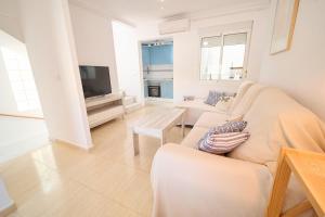 a white living room with a couch and a tv at Soleado adosado esquinero frente a piscina in Gran Alacant