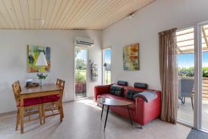 a living room with a red couch and a table at Ølholm Cottage in Stege