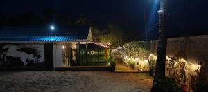 a house with lights on a fence at night at Sabu's Lake and Beach Resort in Mayyanād