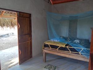 a bedroom with a bed with a blue mosquito net at Mia's House in Nembrala