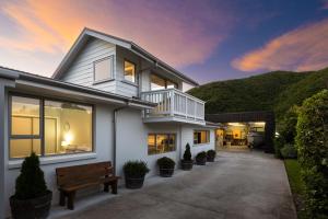 ein weißes Haus mit einer Bank davor in der Unterkunft Beach Road Oasis - Waikawa Holiday Home in Picton