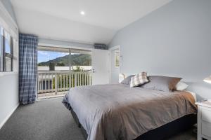 ein Schlafzimmer mit einem Bett und einem großen Fenster in der Unterkunft Beach Road Oasis - Waikawa Holiday Home in Picton